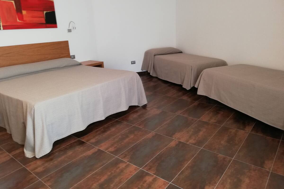 A room with two beds, a wooden headboard, a nightstand, and a red abstract painting on the wall.