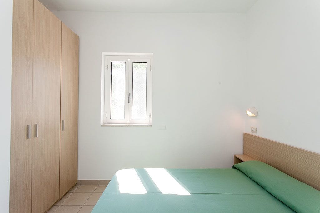 Un dormitorio con cama, ventana y armario.