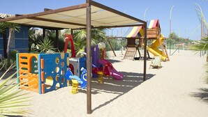 A beach playground with various play structures, including slides and climbing frames, under a shaded area. - Scialì Hotel (Vieste)