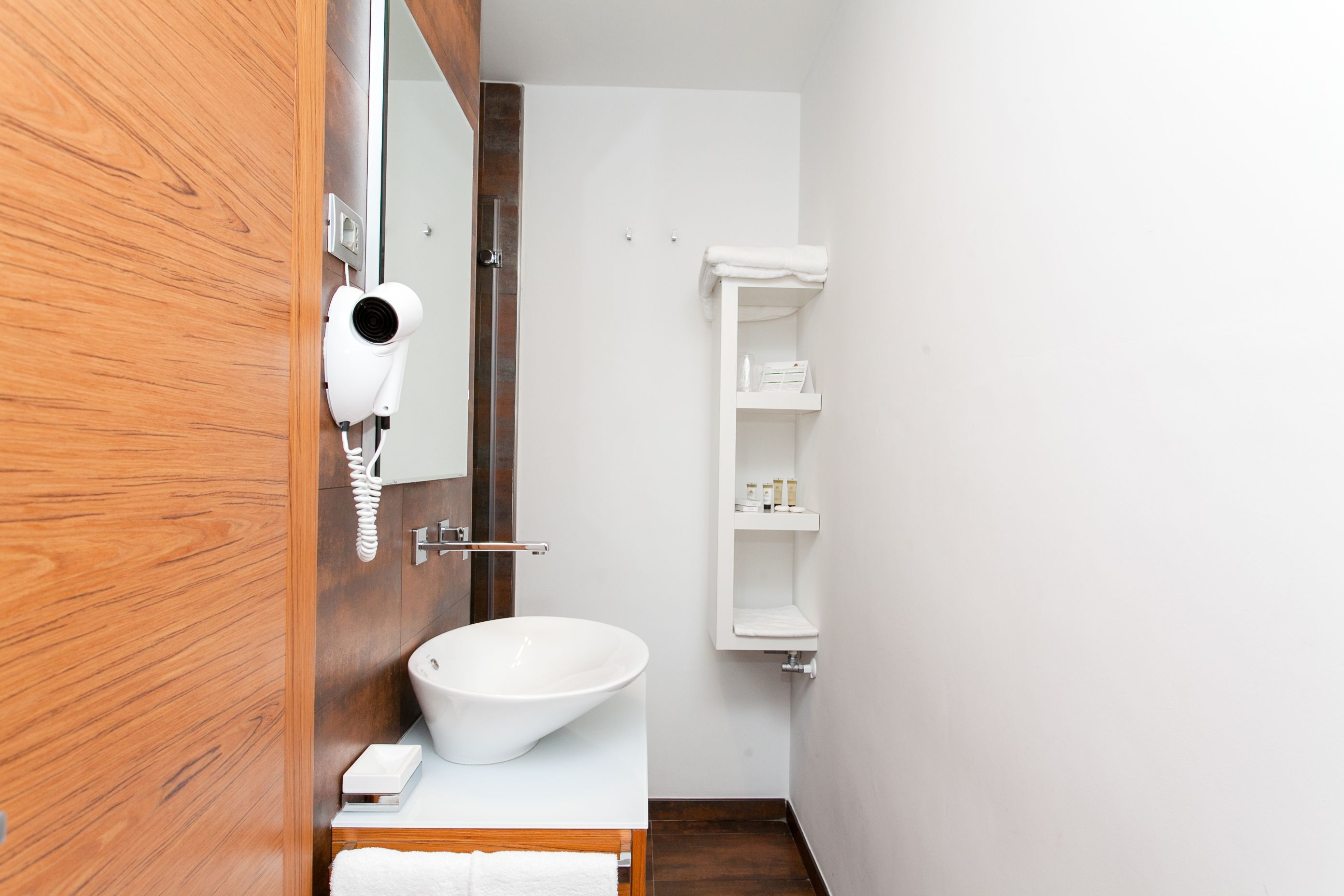 A bathroom with a wooden vanity, a white sink, a towel rack, and a mirror.