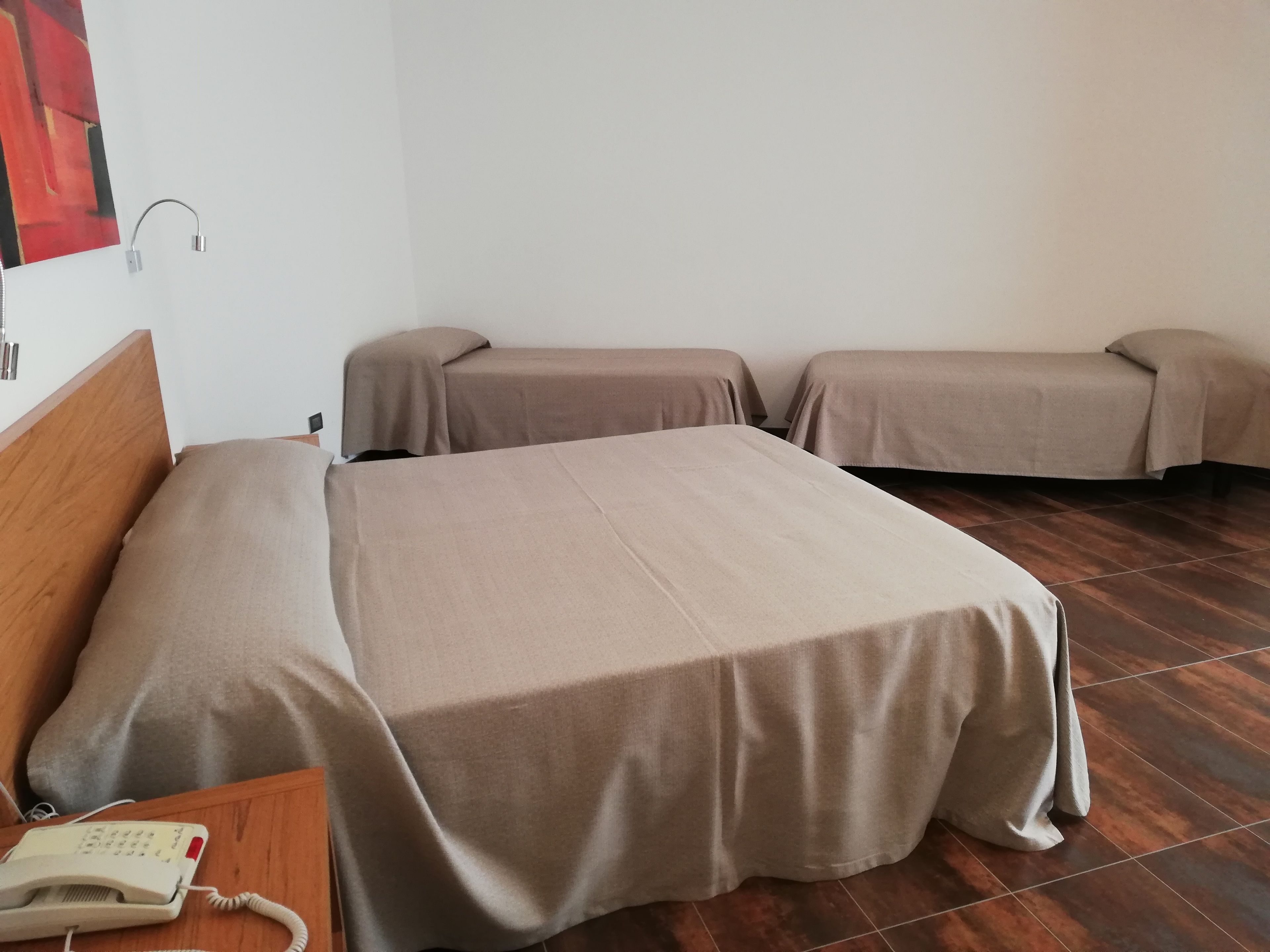 Ein Zimmer mit zwei Betten, einem Holzkopfteil, einem Nachttischtelefon und einer Wandlampe.
