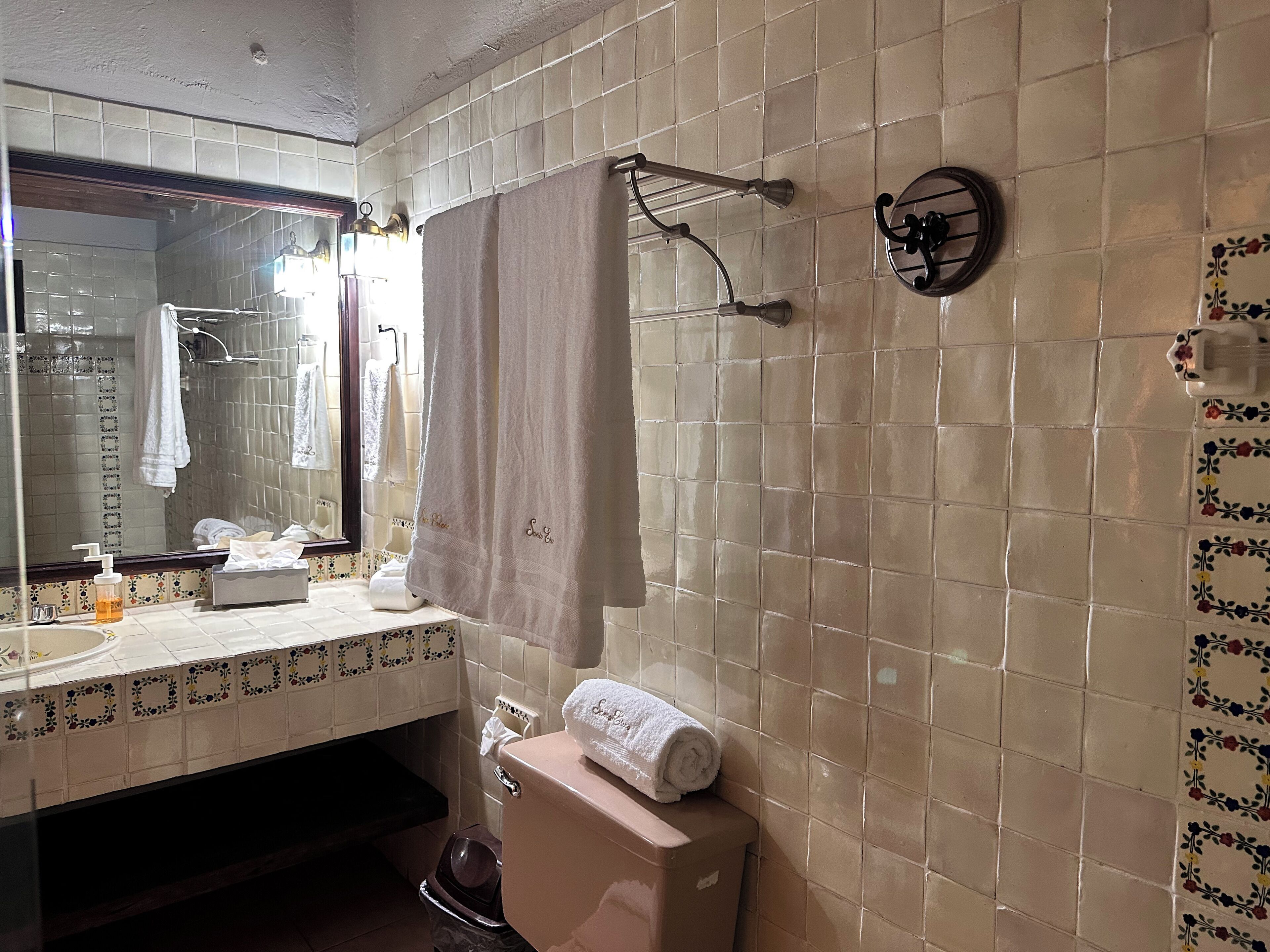 A bathroom with a toilet, sink, and mirror.