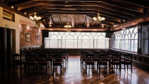 A spacious hall with wooden floors and rows of chairs, large windows with arched designs, and hanging chandeliers. - Hotel María Victoria (Xalapa)