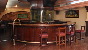 A bar area with a central column, wooden bar counter, and four bar stools. - Hotel María Victoria (Xalapa)