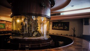A large, round, wooden bar area with a glass enclosure containing a decorative fish tank. - Hotel María Victoria (Xalapa)