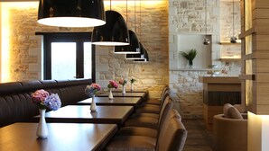 Un restaurante con pared de piedra, mesas de madera y asientos acolchados.