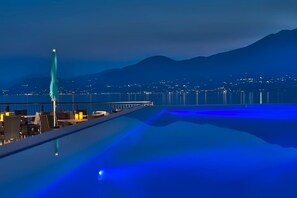 Une piscine à débordement située sur le toit, offrant une vue sur le paysage urbain et les montagnes en arrière-plan.