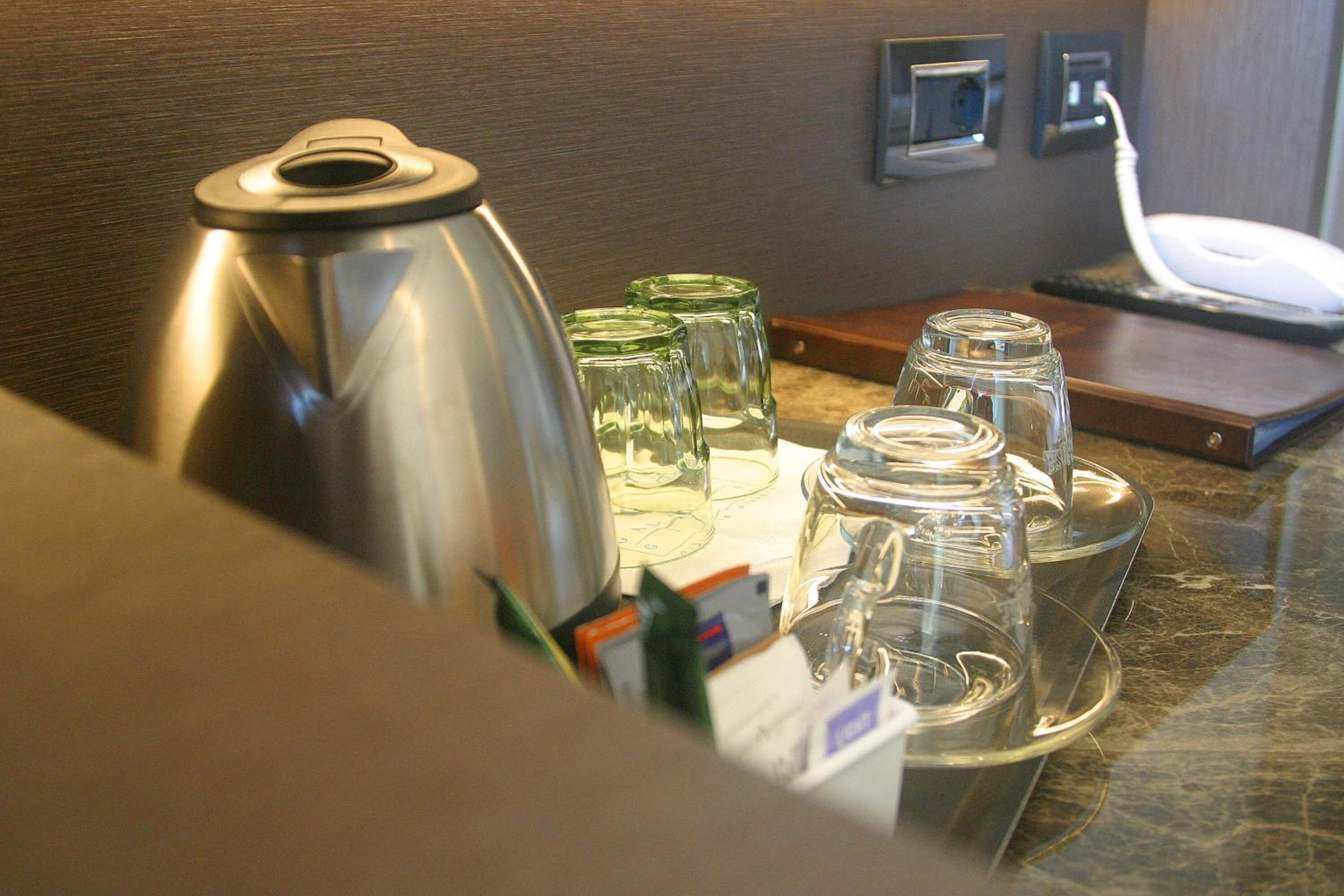 Un plan de travail de cuisine avec une bouilloire en acier inoxydable, plusieurs verres et une machine à café.