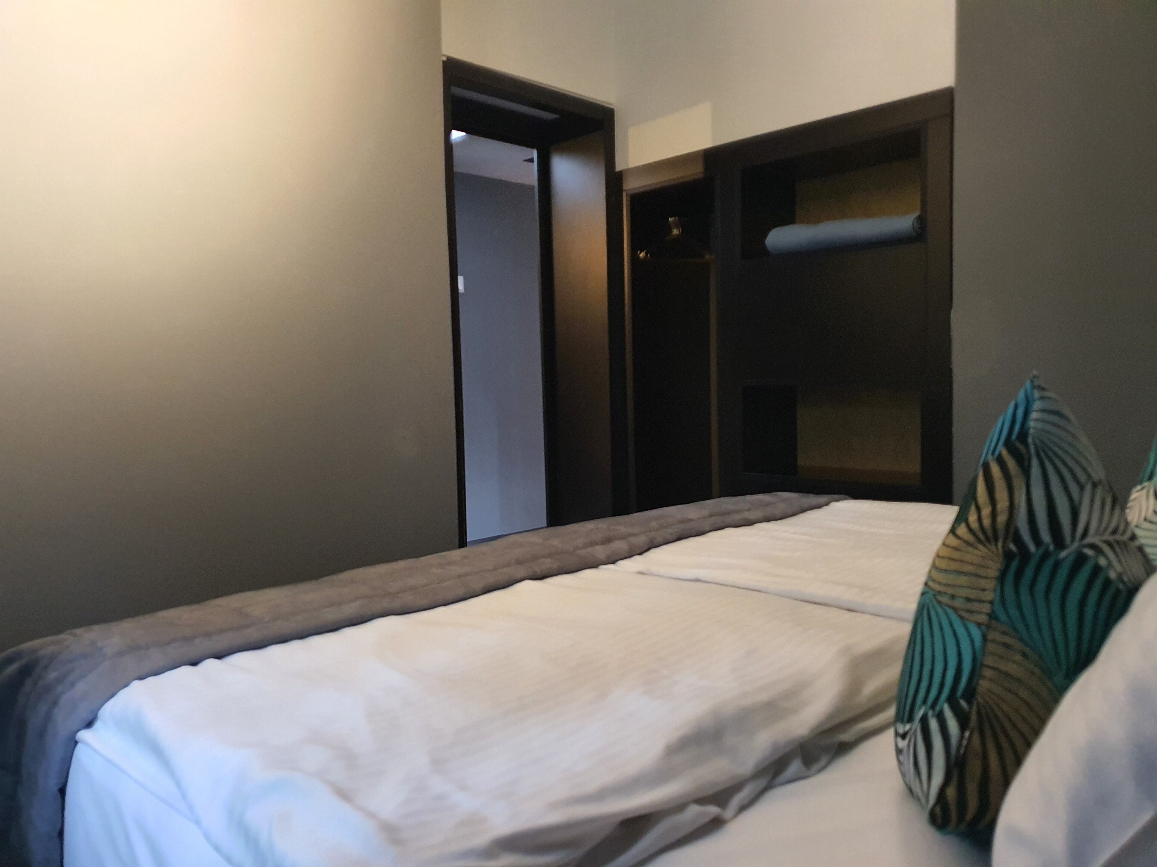 A hotel room with a bed, a wardrobe, and a door leading to another room.