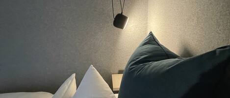 Una habitación con una cama, almohadas y una lámpara colgante.