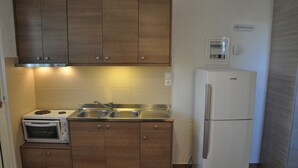 Une cuisine compacte avec des meubles en bois, un four à micro-ondes encastré, un évier et un réfrigérateur.