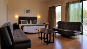 Une chambre d’hôtel comprenant un lit, un canapé, une table basse et un bureau avec une lampe.