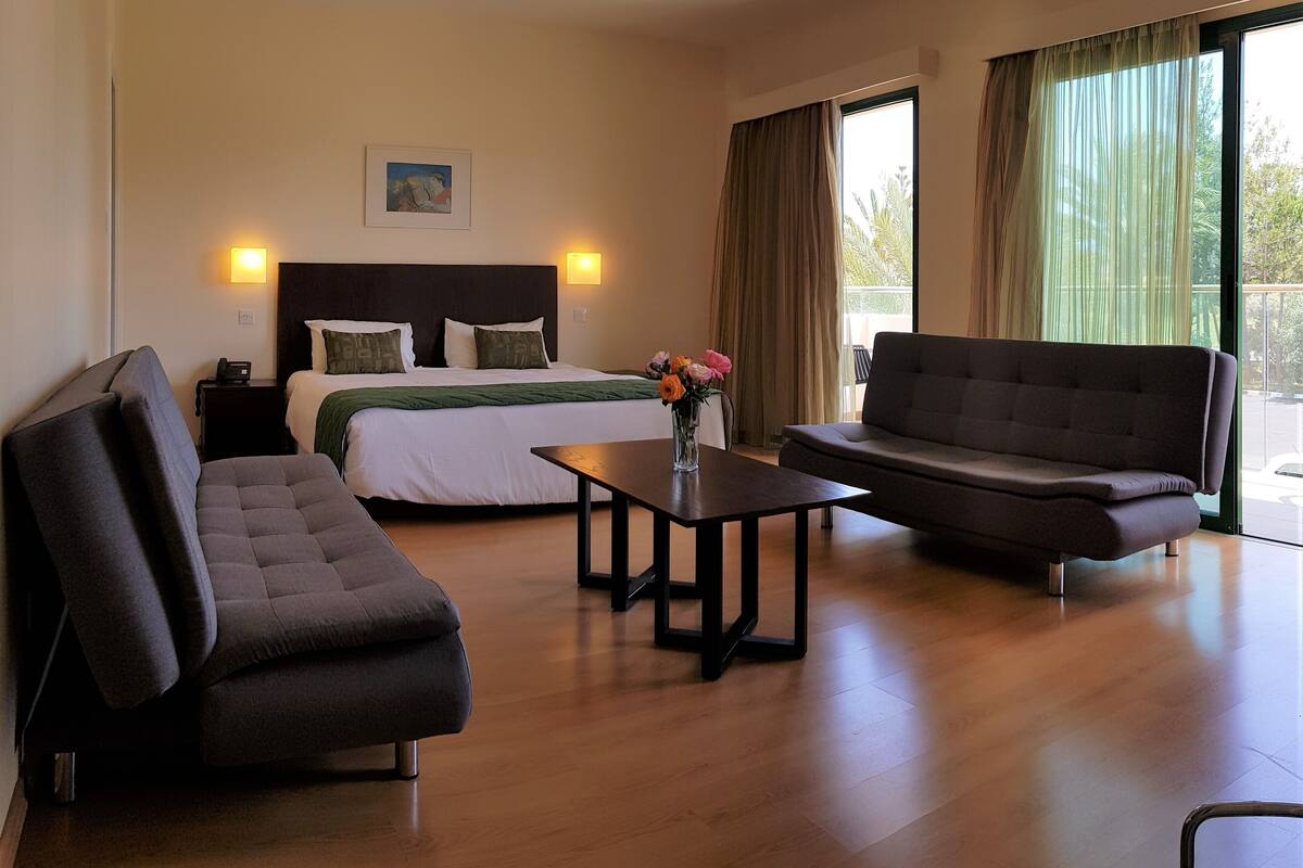 Une chambre d’hôtel comprenant un lit, un canapé, une table basse et un bureau avec une lampe.