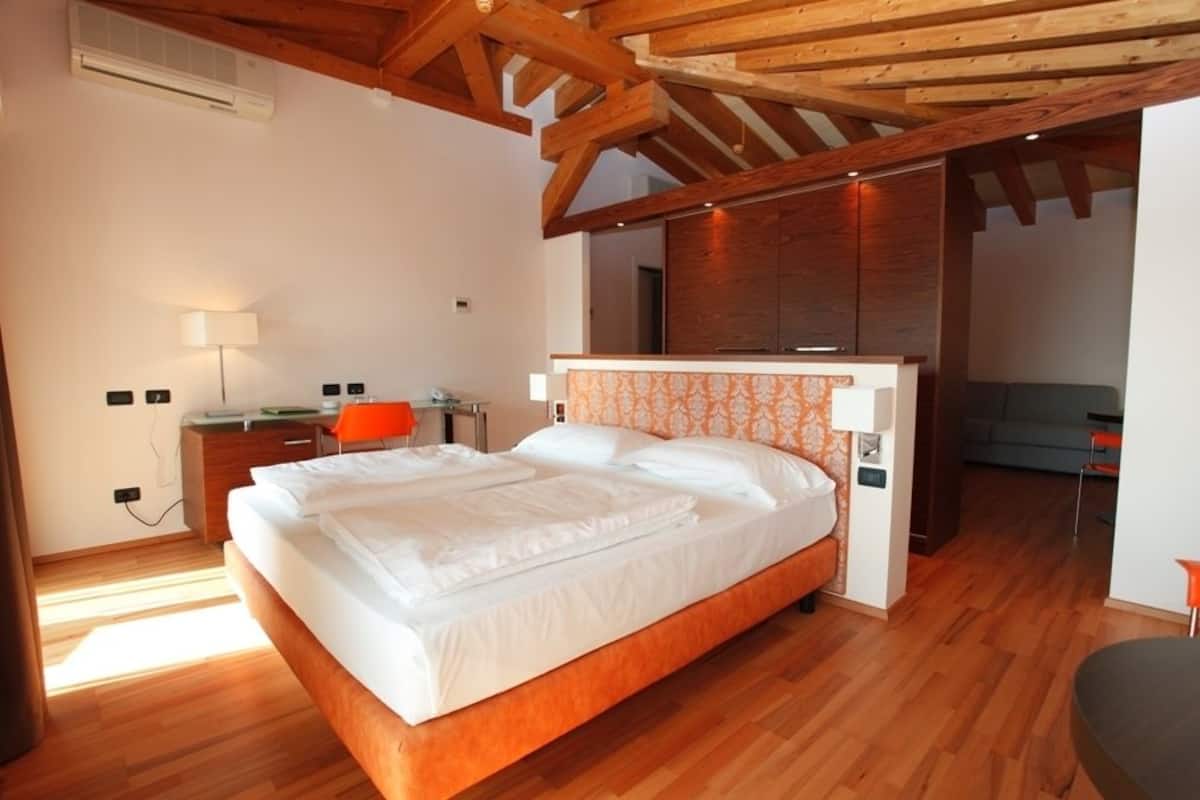 A bedroom with a wooden bed, a desk, and a chair.