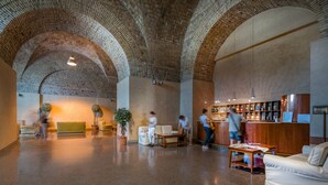 A lobby with arched brick ceilings, a reception desk, seating areas, and a bar. - Villa EUR - Parco dei Pini (Rome)