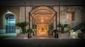 A modern building entrance with a glass canopy, brick walls, and potted plants. - Villa EUR - Parco dei Pini (Rome)