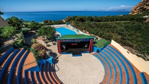 Ein Amphitheater im Freien mit Bühne, Sitzplätzen und Blick aufs Meer.