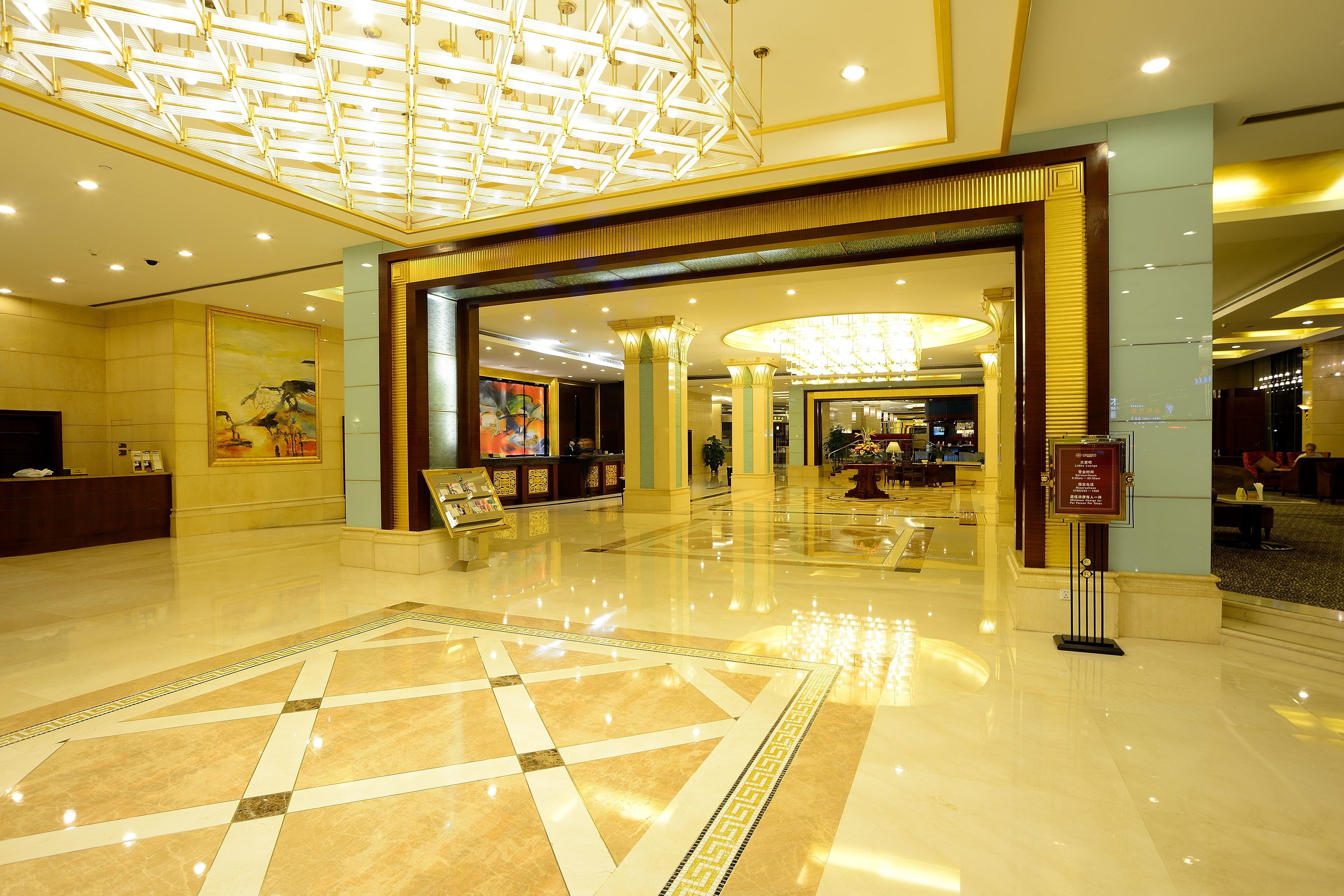 A spacious lobby with a geometric patterned floor, a reception desk, and a large chandelier.