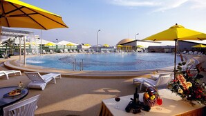 A poolside area with sun loungers, yellow umbrellas, and a table with drinks and flowers. - Hengfeng Haiyue International Hotel (Shenzhen)