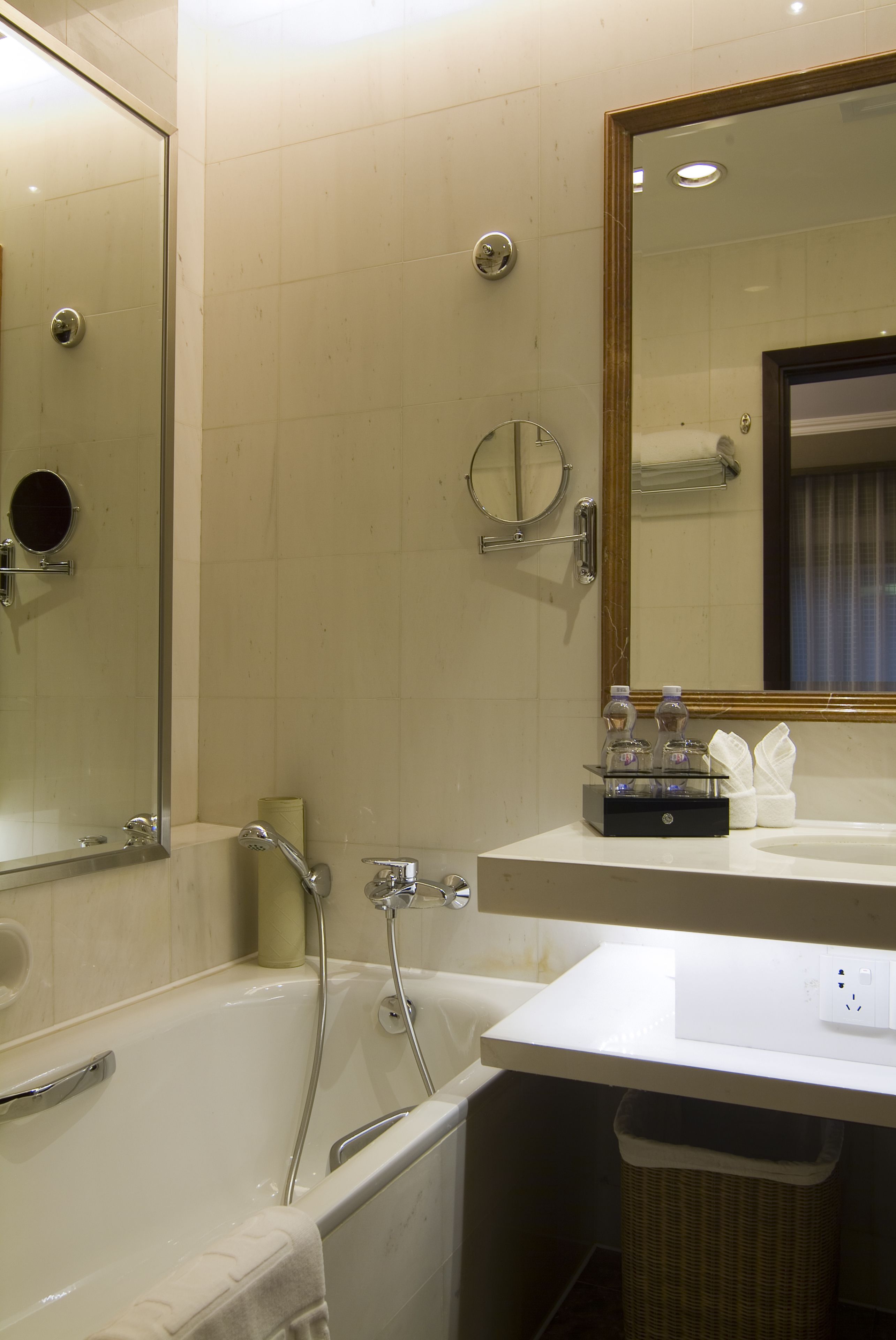 Une salle de bain avec une baignoire, un lavabo, un miroir et une poubelle.