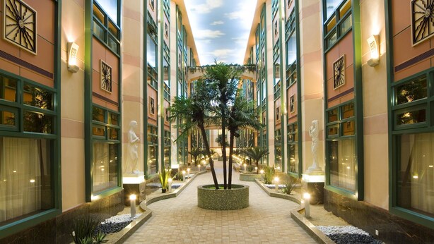 A hotel corridor with a central planter, decorative statues, and a tiled floor. - Hengfeng Haiyue International Hotel (Shenzhen)