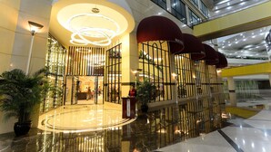 A modern hotel lobby with a circular reception area, a large potted plant, and a red awning. - Hengfeng Haiyue International Hotel (Shenzhen)