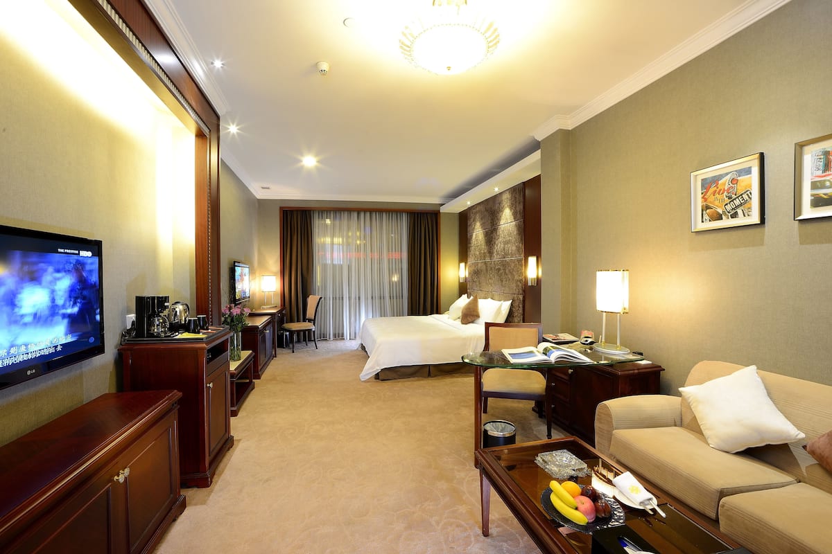 Una habitación de hotel con una cama, televisión, escritorio, sofá y mesa de centro.
