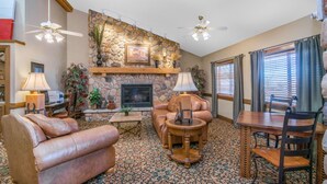 A living room with a stone fireplace, leather sofa, and a dining table with chairs.