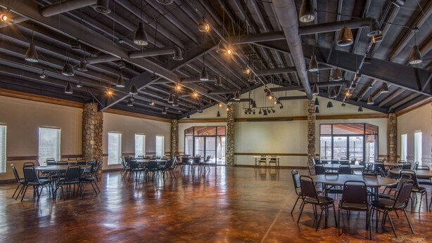 A spacious hall with high ceilings, exposed beams, and multiple tables and chairs arranged for meetings.