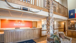A lobby with a reception desk, a stone pillar, a patterned armchair, and a flag.