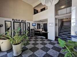 Zona de recepción con mostrador de entrada, una escalera y un letrero que dice 'RESTO NOVO'.
