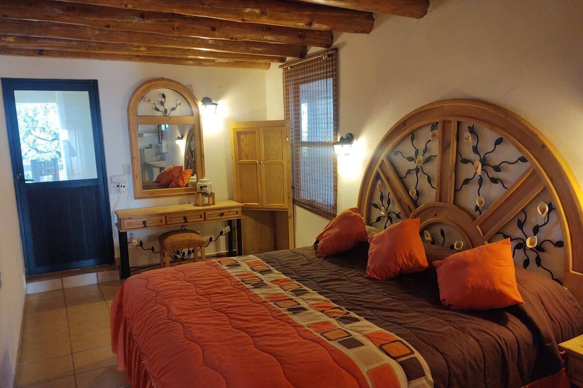 A bedroom with a bed, a dresser, a mirror, and a window with blinds.