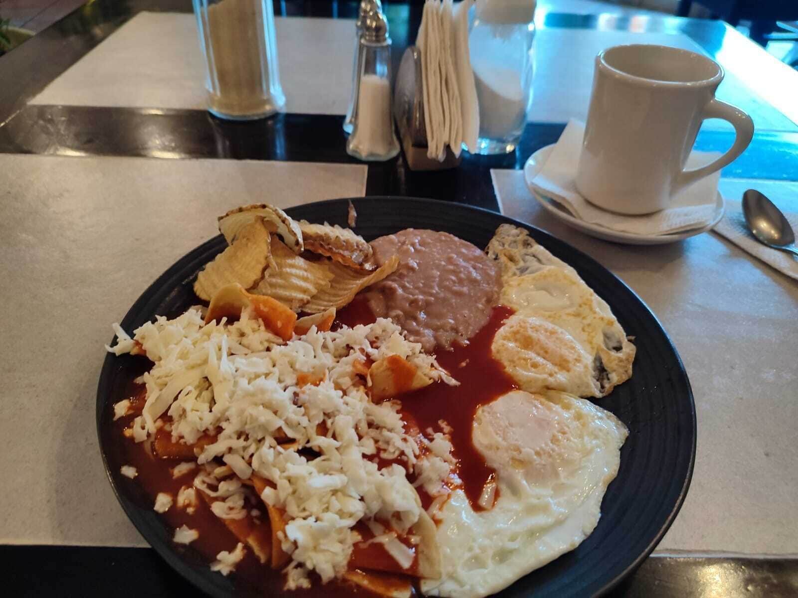 A plate with rice, beans, eggs, and a slice of meat.