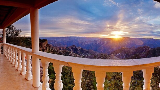 Ein Balkon mit Blick auf ein Gebirge bei Sonnenuntergang.