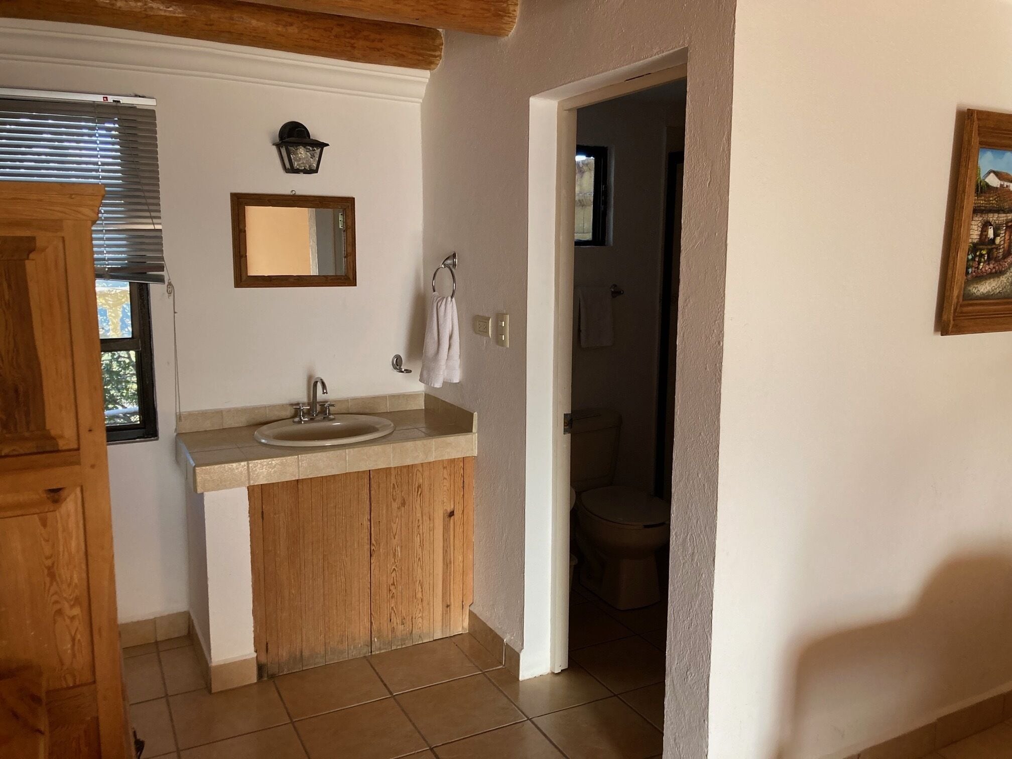 Un baño con tocador de madera, un lavabo y un espejo.