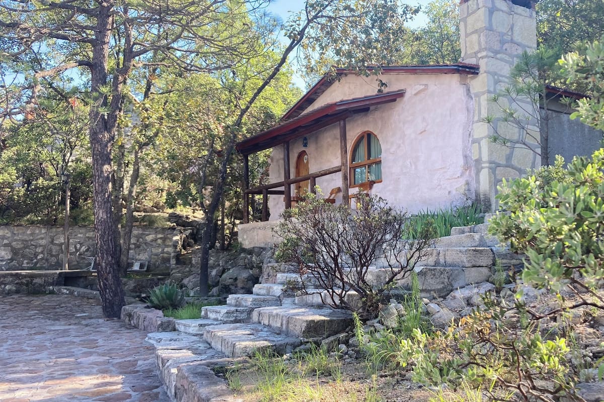A stone building with a rustic appearance, featuring a small porch and arched windows.