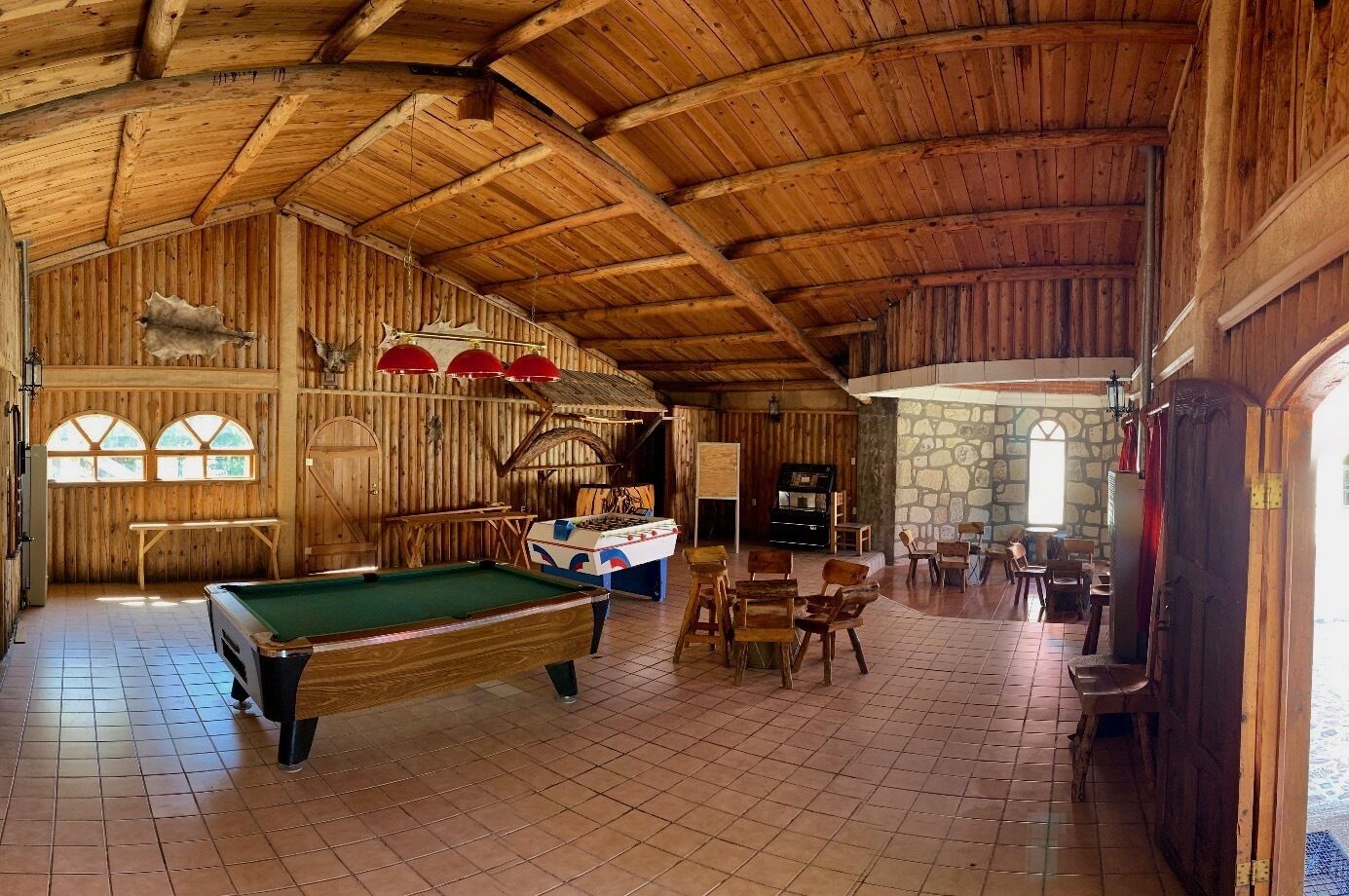 Ein Holzinterieur mit Billardtisch, einer Sitzecke und einer Steinwand.
