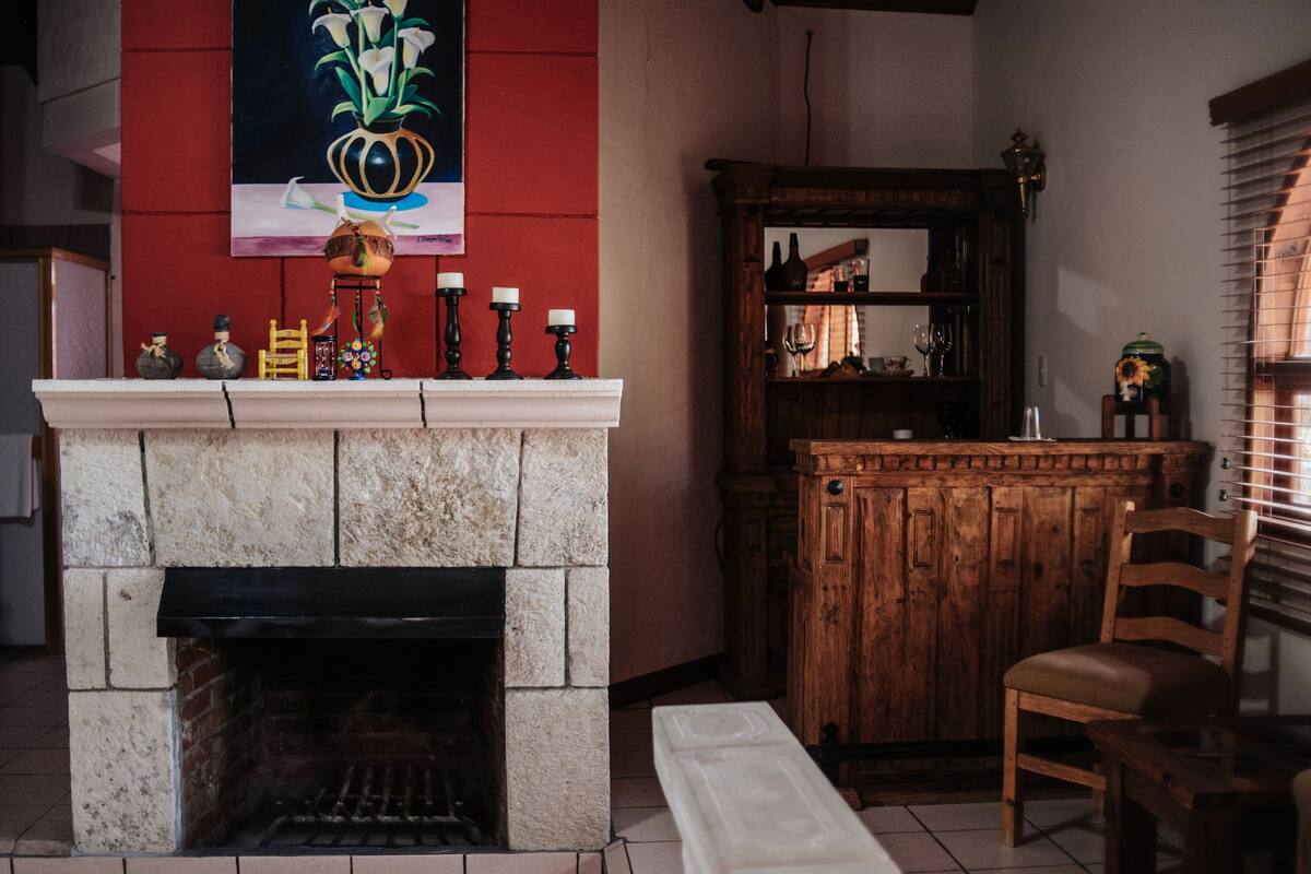 A stone fireplace with a mantel, a wooden cabinet, and a chair.