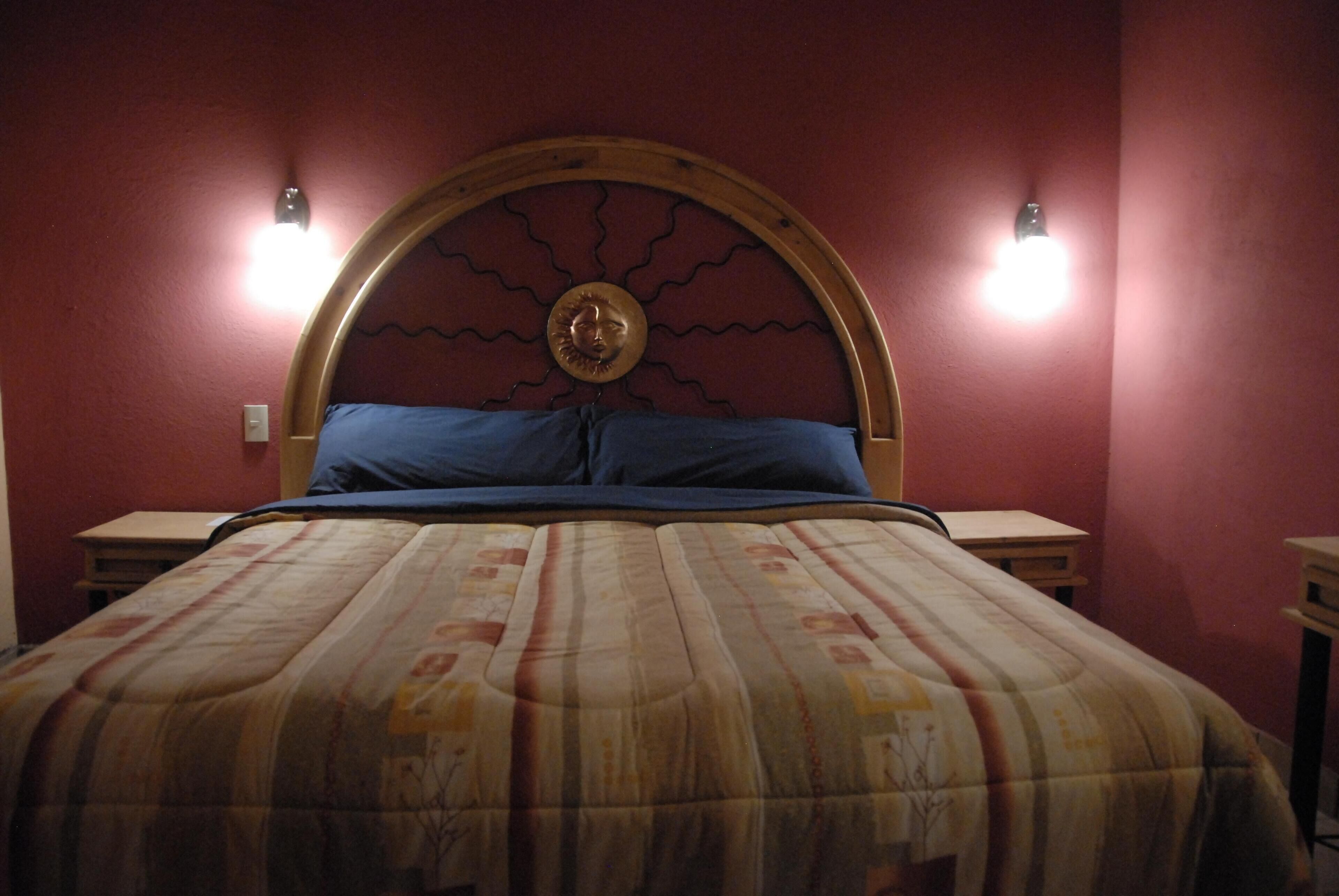 A bed with a wooden headboard, two bedside lamps, and a patterned bedspread.