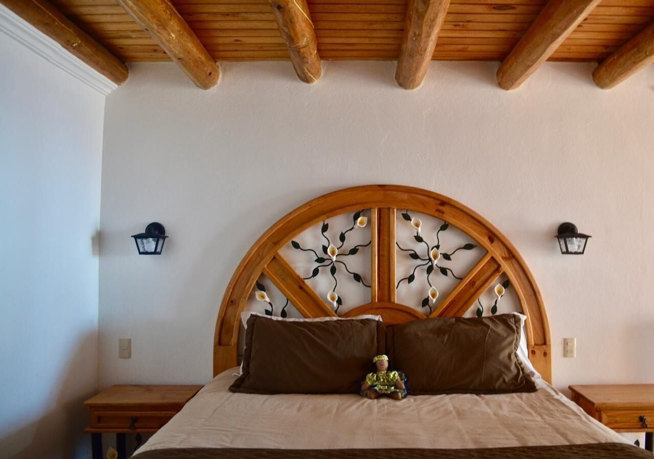 A bedroom with a wooden headboard, two bedside tables, and a nightstand.