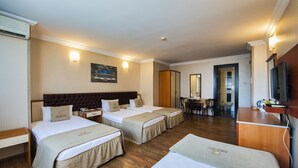 Habitación de hotel con dos camas, un escritorio, una silla, un televisor y un baño visible a través de una puerta abierta.
