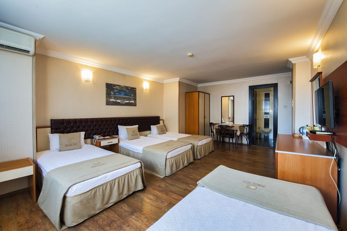 Camera d'albergo con due letti, una scrivania, una sedia, una televisione e un bagno parzialmente visibile attraverso una porta aperta.