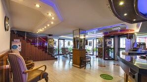 Un vestíbulo de hotel con mostrador de recepción, zona de estar y una escalera.