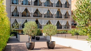 A multi-story hotel with balconies, large windows, and potted plants in the foreground. - H10 Art Gallery (Barcelona)