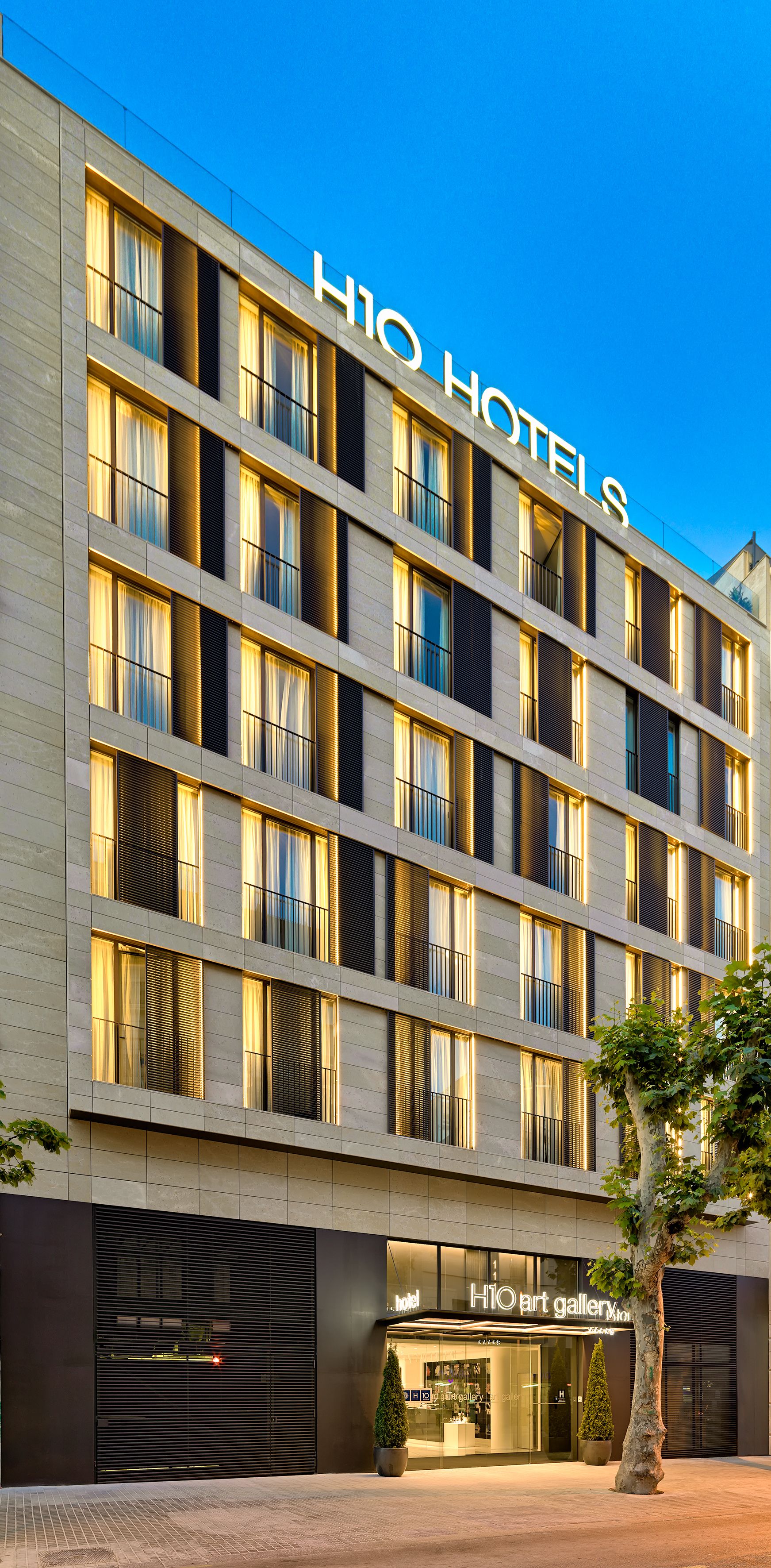 A hotel building with multiple floors, large windows, and a visible art gallery entrance.