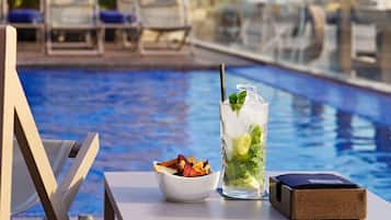 Een buitenzwembad, ligstoelen bij het zwembad