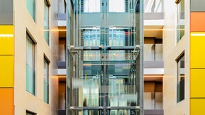 Een modern gebouw met een centraal liftkanaal, meerdere verdiepingen en grote ramen.