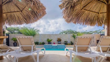 Relax by the pool surrounded by lush greenery and comfortable lounge chairs.