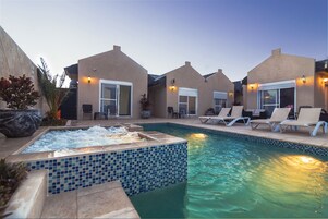 Zona de piscina con sillones de descanso y una bañera de hidromasaje.