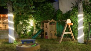 Zona de juegos infantiles con tobogán, columpio y arenero.